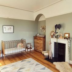 a baby's room with a fireplace, dresser and crib