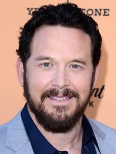 a close up of a person wearing a suit and tie with a beard smiling at the camera