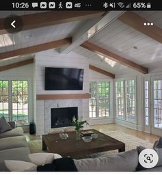 a living room with couches and a tv mounted on the wall in front of a fireplace