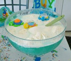 a bowl filled with ice cream and toys on top of a table next to a birthday cake