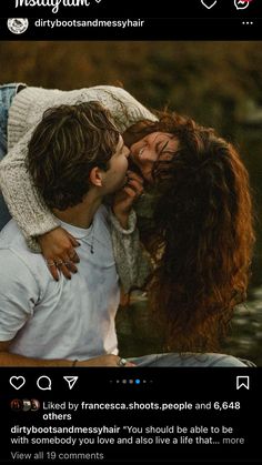 two people kissing each other in front of water