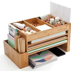 a wooden desk organizer with drawers filled with office supplies and stationery items on top