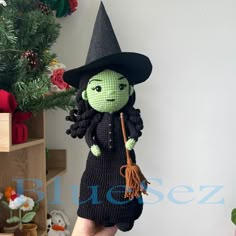 a crocheted witch doll holding a broom