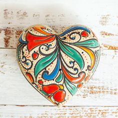 a decorative heart shaped box sitting on top of a white wooden table next to a wall