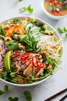 a white bowl filled with salad next to two bowls of soup and chopsticks