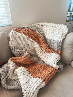 an orange and white blanket sitting on top of a couch