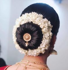 a close up of a woman with flowers in her hair and an elaborate brooch