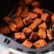 fried food being cooked in an air fryer with the lid open to show it's meat cubes