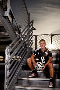 a young man sitting on steps holding a soccer ball