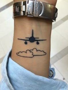 a woman's wrist with an airplane tattoo on the left side of her arm