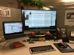 an office cubicle with two computer monitors, keyboard and mouse on the desk next to each other