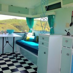 a kitchen area with a table, sink and window in the back side of a camper