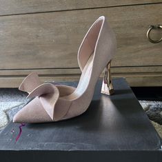 a pair of high heeled shoes sitting on top of a black box in front of a dresser