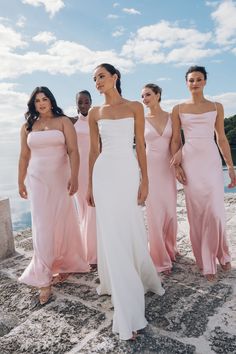 bridesmaids in pink dresses standing on the beach