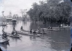 an old black and white photo of people in canoes