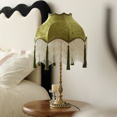 a table with a lamp on it next to a bed