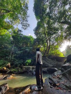 a man standing on top of a rock next to a river