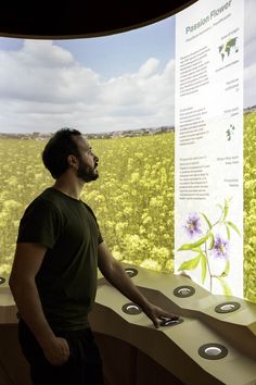 a man standing in front of a display with flowers on the wall and other information about plants