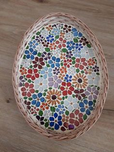 a basket with flowers painted on it sitting on a wooden floor next to a wall