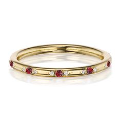 a yellow gold ring with red and white stones