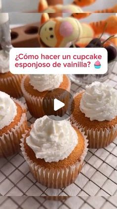 cupcakes with white frosting sitting on top of a cooling rack next to stuffed animals