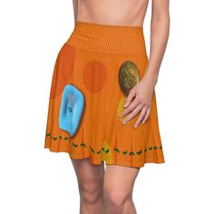 a woman wearing an orange skirt with a blue button on the side and her hand in her pocket