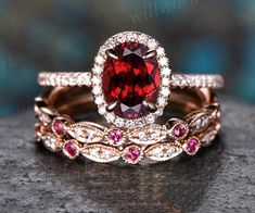 a close up of two wedding rings with a red stone in the middle and white diamonds on top