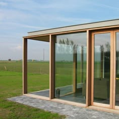 an outdoor room with sliding glass doors on the outside and green grass in the background