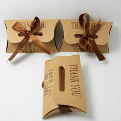 two boxes with brown ribbon tied around them on a white surface, one is open and the other has a tag that says thank you