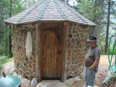 a man standing in front of a stone structure with a wooden door and grill on the outside