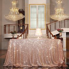 a table with a gold sequined cloth and chandelier hanging from the ceiling