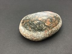 a close up of a rock on a black surface with white and orange speckles