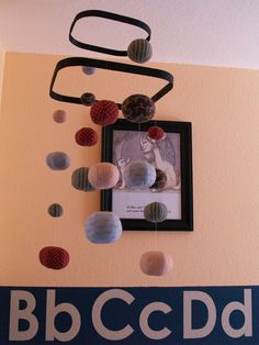 a photo frame hanging on the wall with paper balls in front of it and an abc ccd logo below