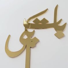 an arabic calligraphy is shown on a white surface with gold trim and metal accents