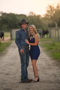 a man and woman standing on a dirt road