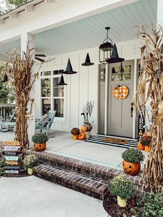 the front porch is decorated for halloween with pumpkins and cornstatches on it