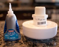 a bottle of glue sitting on top of a counter next to a container with a liquid in it