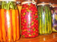 jars filled with different types of vegetables sitting on top of a wooden shelf next to each other