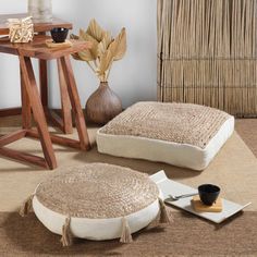 two round pillows sitting on top of a rug next to a table with a vase