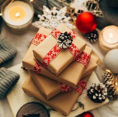 a pile of wrapped presents sitting on top of a table next to candles and christmas decorations