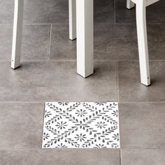 a white and black floor mat sitting on top of a tile floor next to two chairs