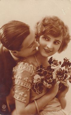 an old black and white photo of two women hugging each other with flowers in their hands