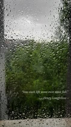 rain is falling down on the window and trees in the background with an inspirational quote