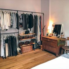 a bedroom with a bed, dresser and clothes rack