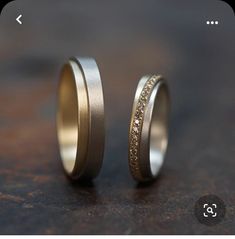 two gold wedding bands with white and yellow diamonds set in them on top of a table