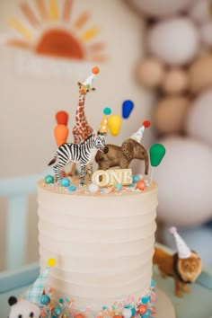 a birthday cake with animals and balloons on the top is decorated in white frosting