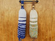 two crocheted objects hanging from hooks on a wooden wall with wood paneling