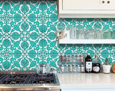 a stove top oven sitting inside of a kitchen next to a wall covered in blue and white tiles