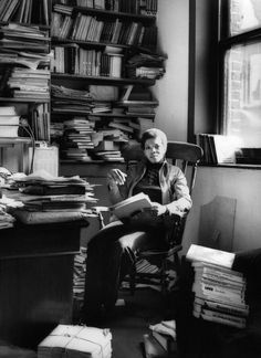 a man sitting in a chair next to a book shelf filled with books