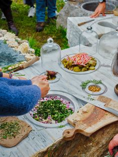 people are preparing food at an outdoor table